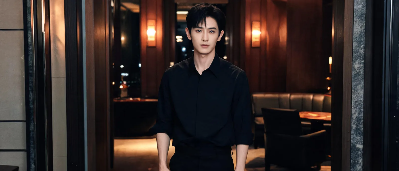 身穿深黑襯衫的年輕男性站在暖橘燈光的包廂通道,示意男模會館與男傳播兩種夜間消費場景的差別