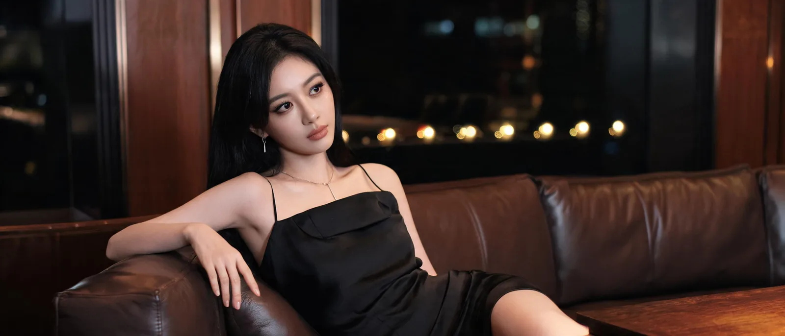 年輕女性斜坐在包廂的進口皮革沙發轉角，示意五樓VIP區的包廂規格差異